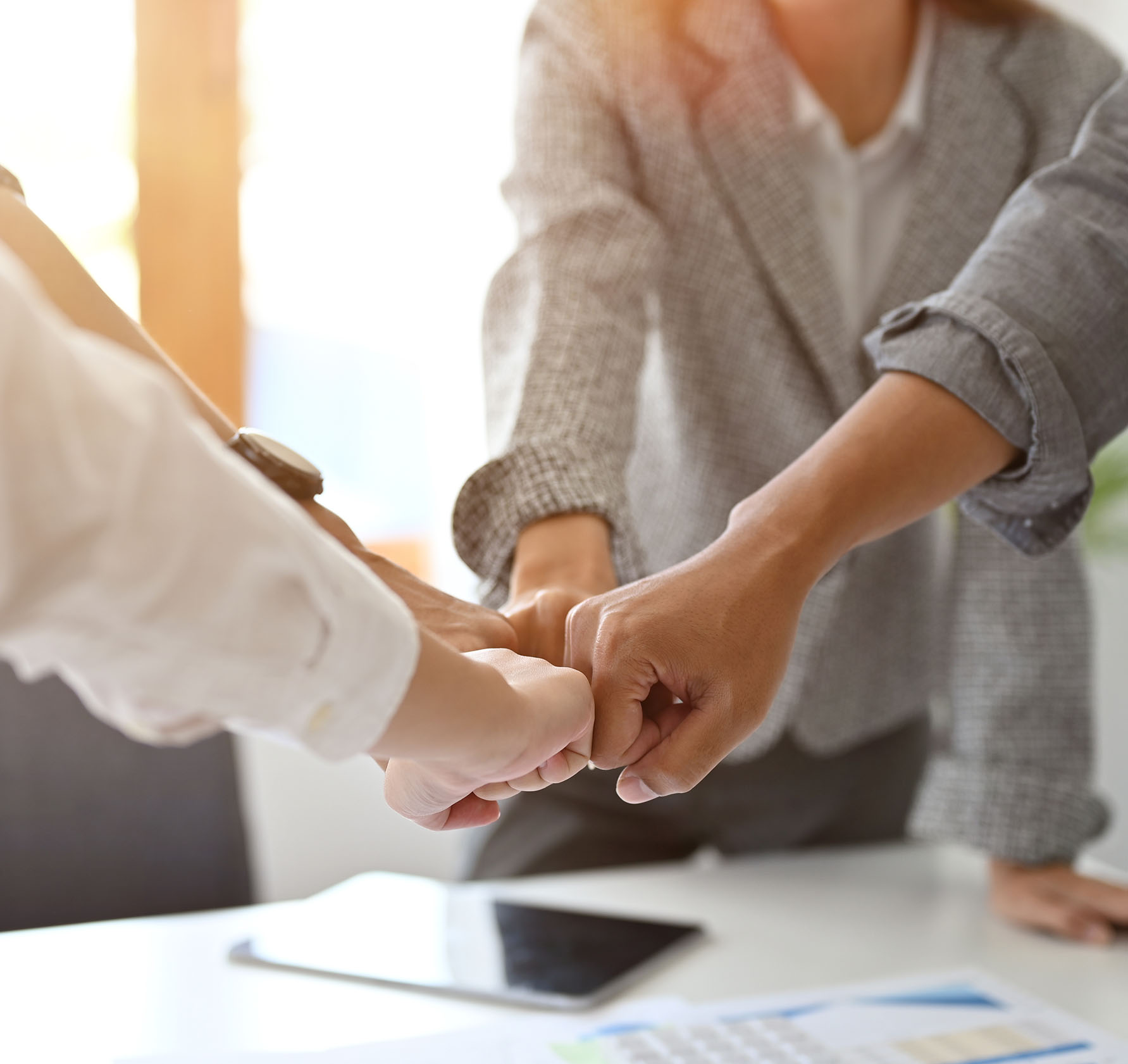 A group of businesspeople making fist bump over the meeting table after the business conference together. Teamwork and team spirit concept